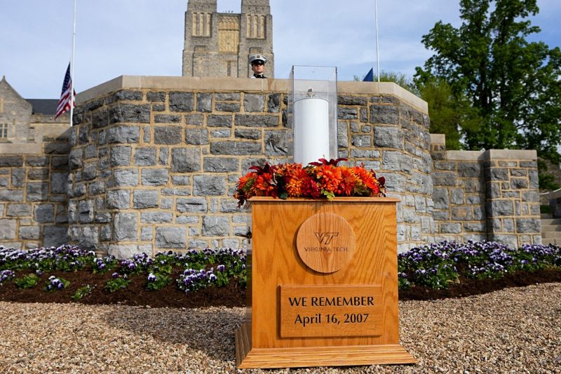 A lit candle sits on a wooden pedastel with the words "We Remember - April 16, 2007"