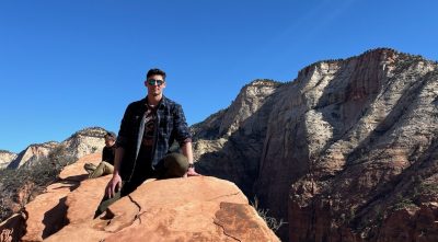 Undergraduate Virginia Tech student sitting on a rock while on a hiking trail.