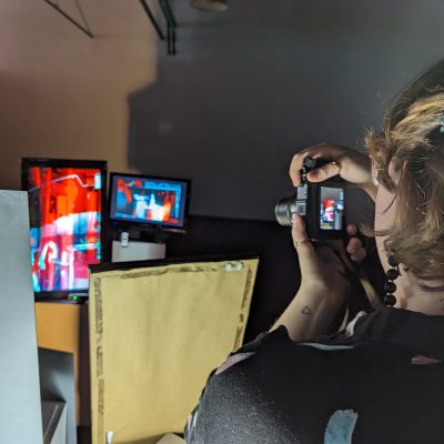 Back of student's head taking a photo of light display work.
