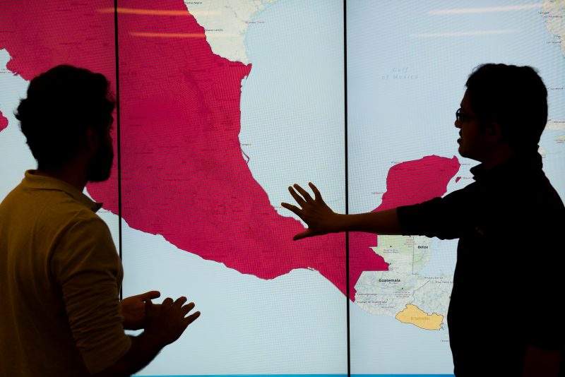 Graduate students in the Discovery Analytics Center with displays from the EMBERS Project at Virginia Tech's Arlington Research Center. EMBERS is a system for forecasting societal significant societal events from open source surrogates.